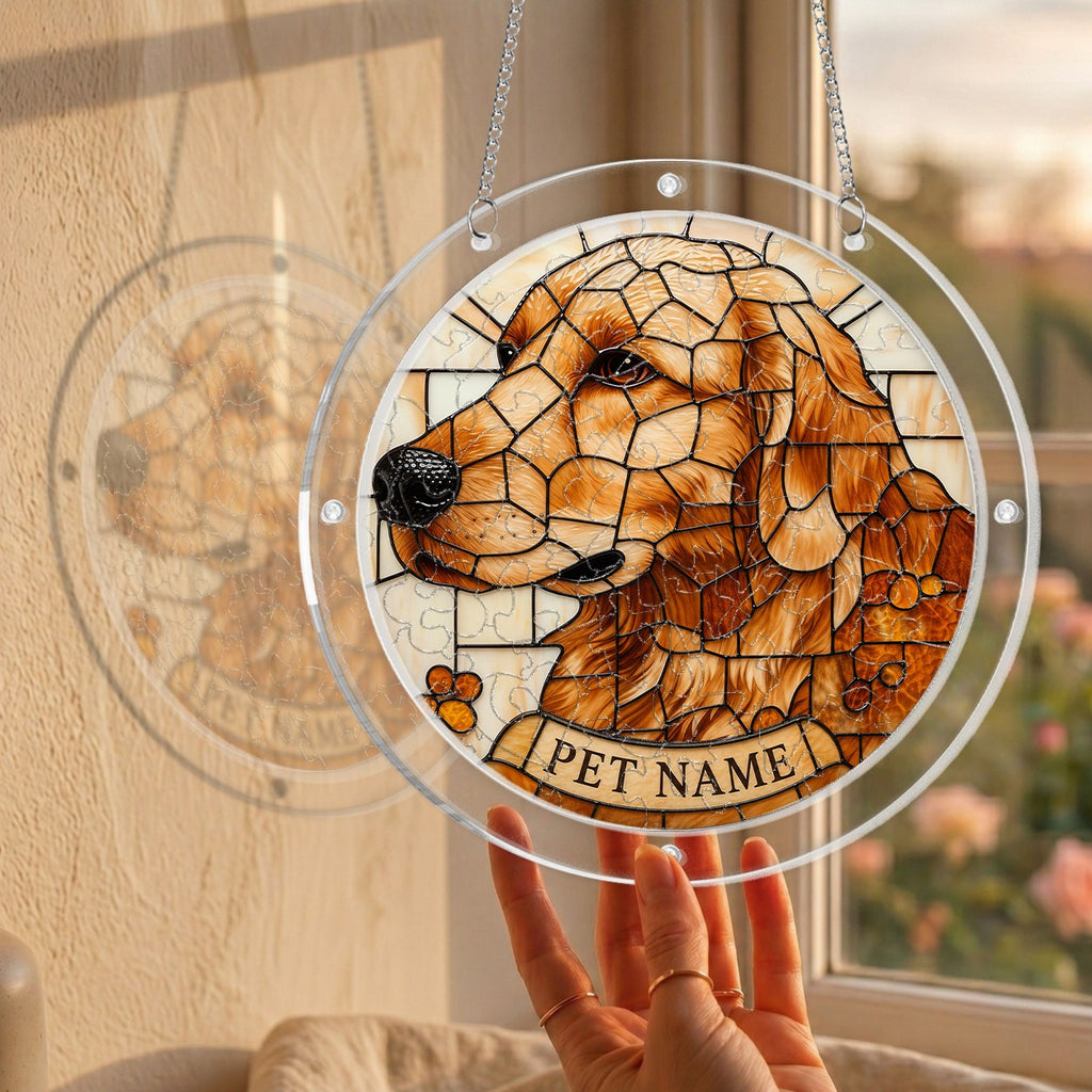 Hand holding the golden mosaic dog memorial puzzle suncatcher up to a sunlit window