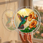 Hummingbird trumpet-flower puzzle suncatcher held up to a sunlit window by hand