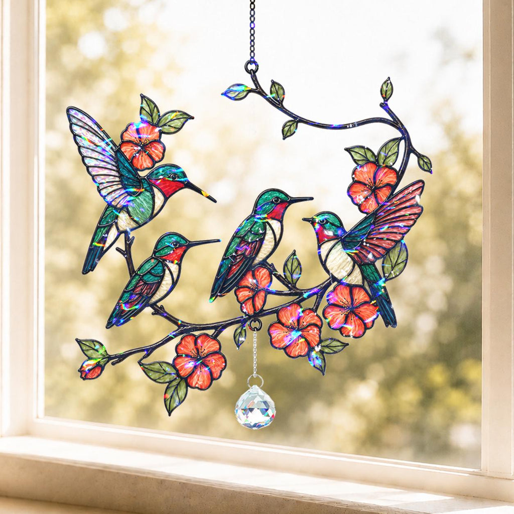 Stained glass panel with colorful hummingbirds and flowers on a window sill.