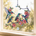 Stained glass panel with colorful hummingbirds and flowers on a window sill.