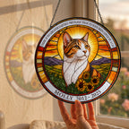 Cat memorial suncatcher held up to a sunlit garden window