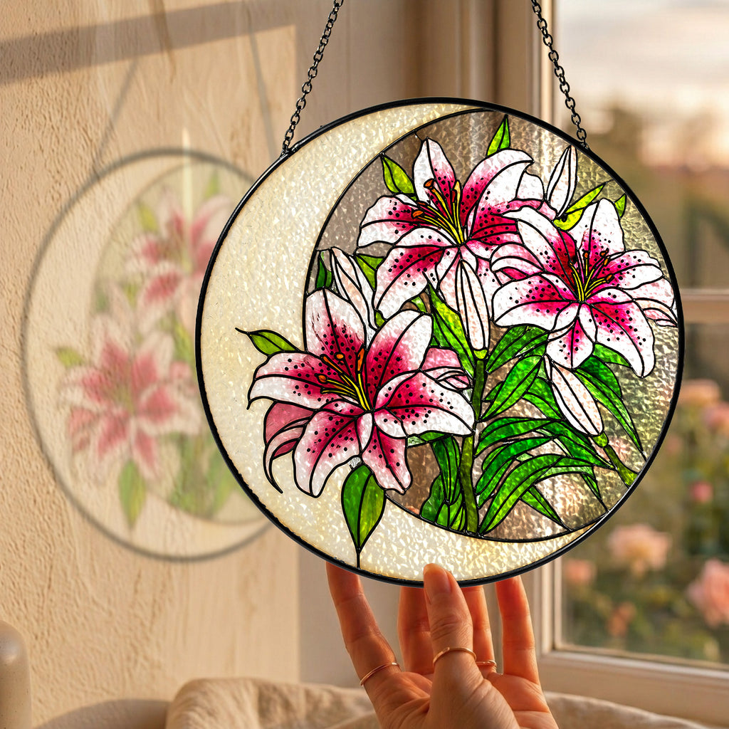 Pink lily stained glass suncatcher hanging in a sunny window with a garden view