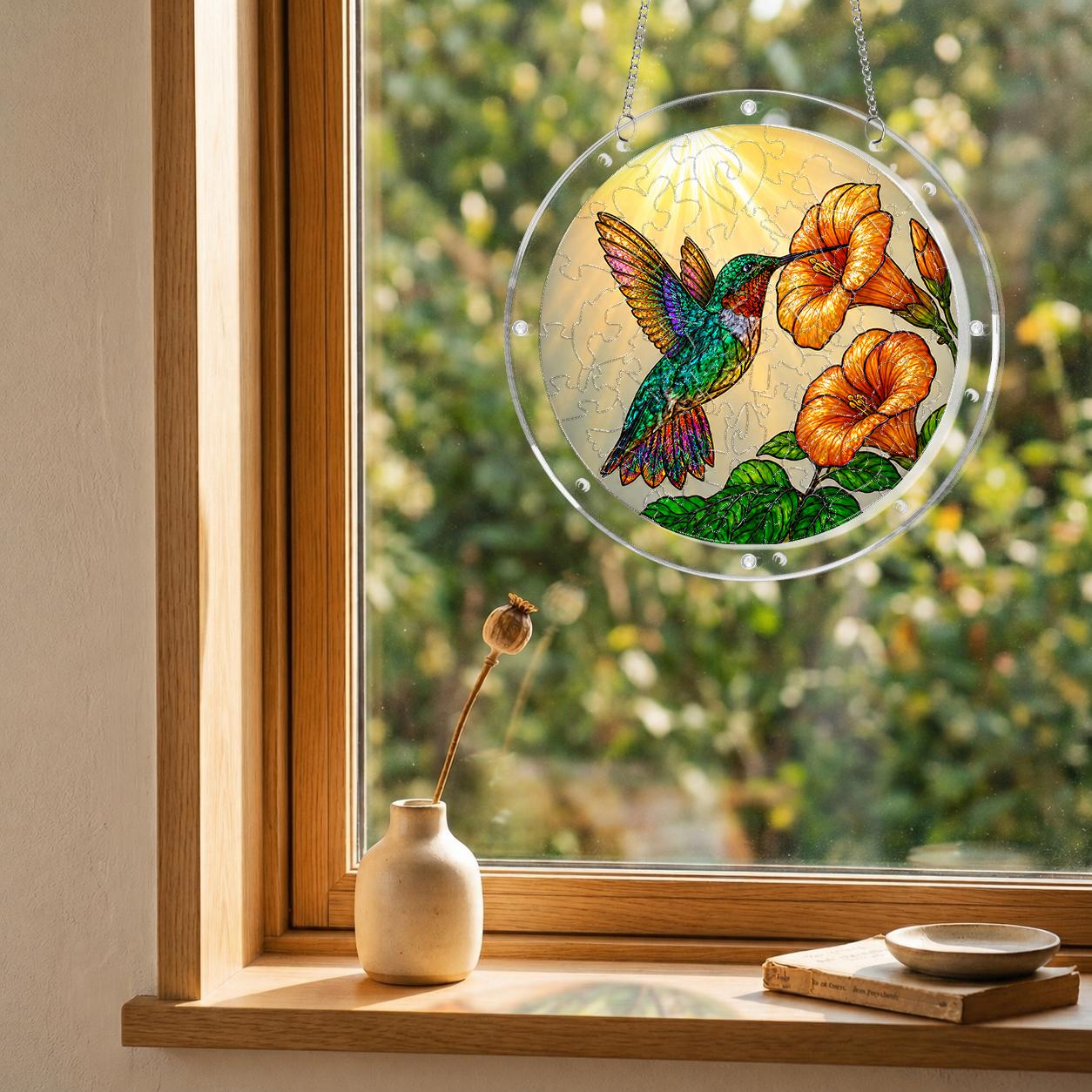 Hummingbird trumpet-flower puzzle suncatcher hanging in a wooden window with a garden view