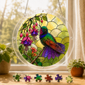 Round hummingbird fuchsia acrylic puzzle suncatcher hanging in a sunny window with colorful puzzle pieces below
