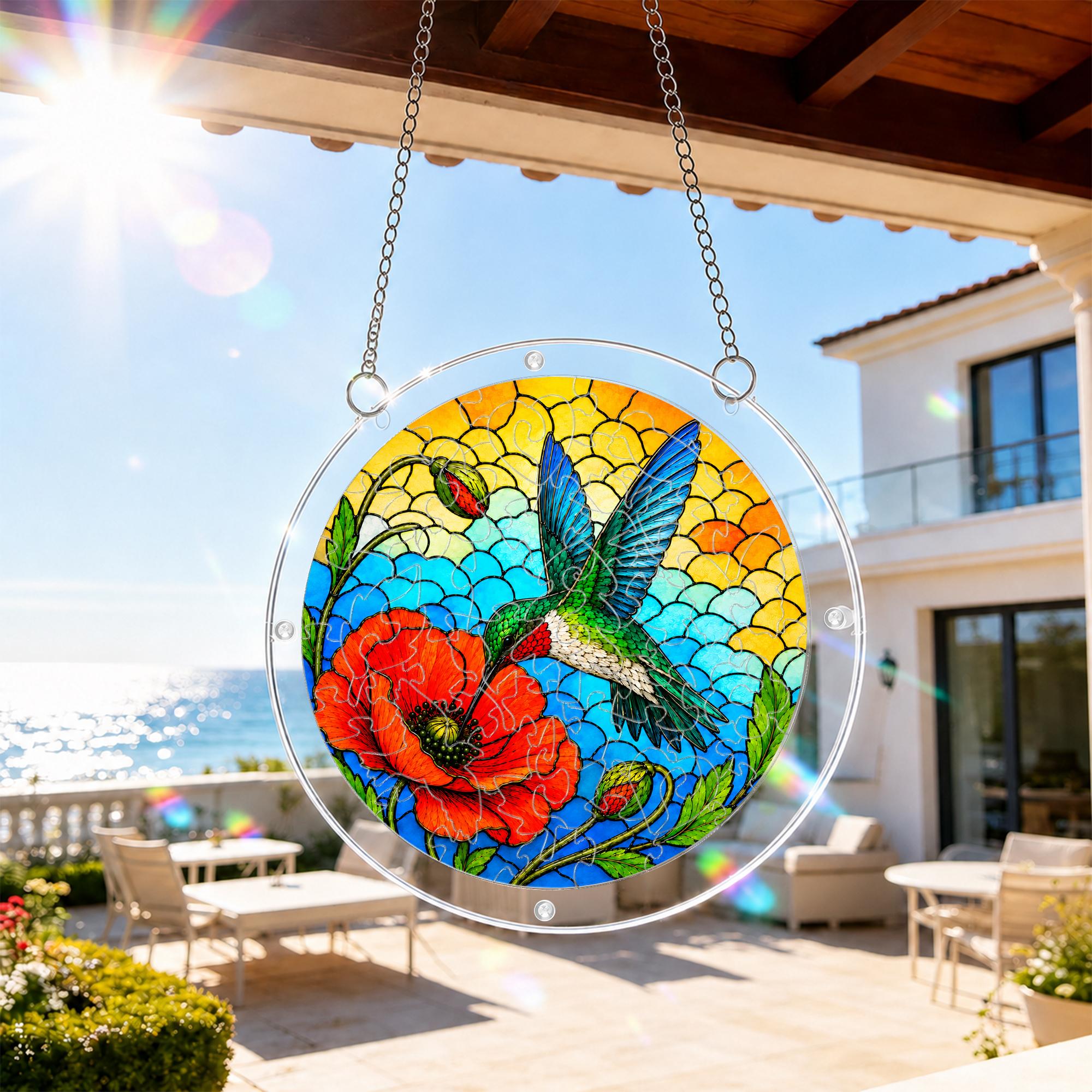 Hummingbird poppy acrylic puzzle suncatcher hanging on an outdoor patio window with a sunny balcony view