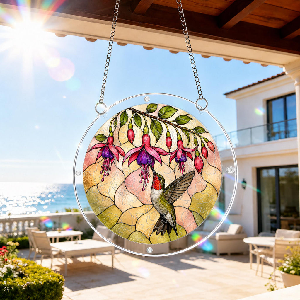 Hummingbird fuchsia acrylic puzzle suncatcher hanging on an outdoor patio window with a sunny balcony view