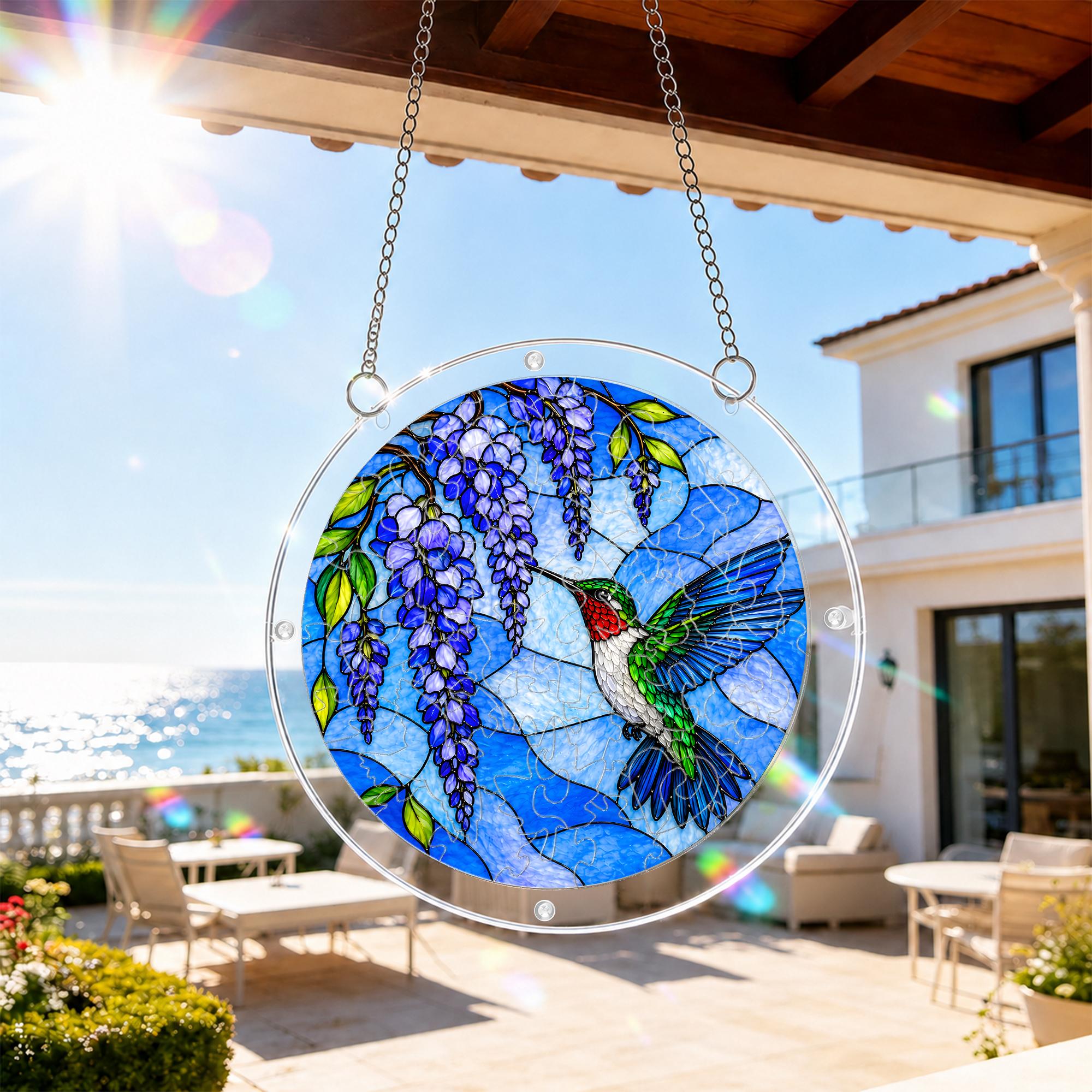 Hummingbird blue wisteria acrylic puzzle suncatcher hanging on an outdoor patio window with bright daylight