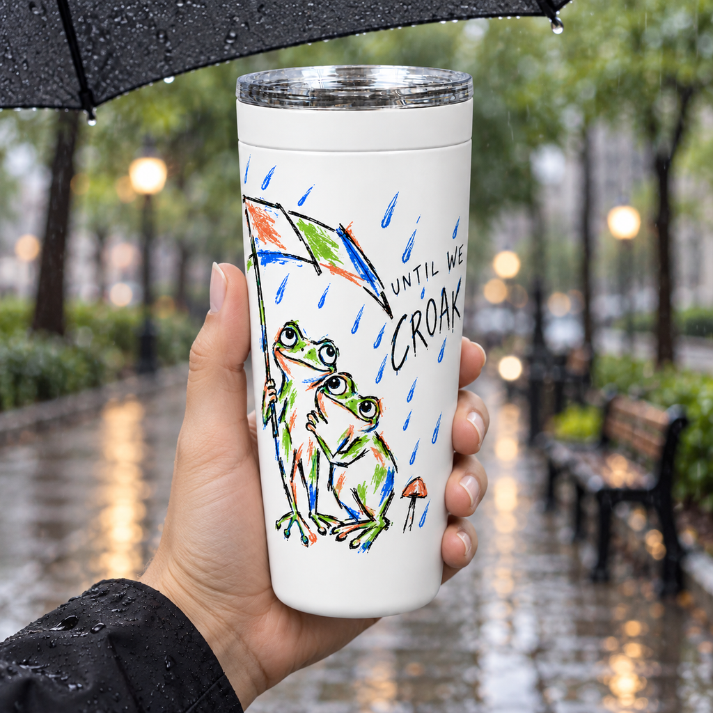 Hand holding the Until We Croak frog couple tumbler under an umbrella in the rain
