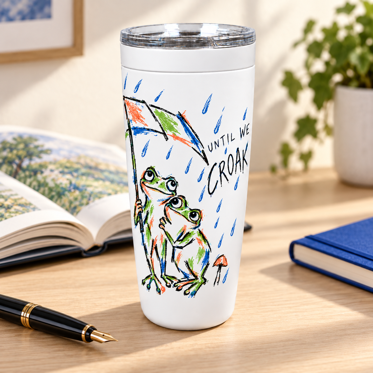 Until We Croak frog couple tumbler on a desk beside an open book