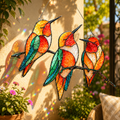 Colorful Triple Hummingbirds holographic acrylic suncatcher hanging in a sunny garden patio, casting rainbow reflections and colorful bird shadows on the wall.