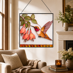 Hummingbird fuchsia stained glass suncatcher displayed in a cozy living room near an armchair, round table, candle, and fireplace mantel.