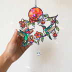 Close up of hand holding hummingbird fuchsia sunset holographic acrylic suncatcher on wall background