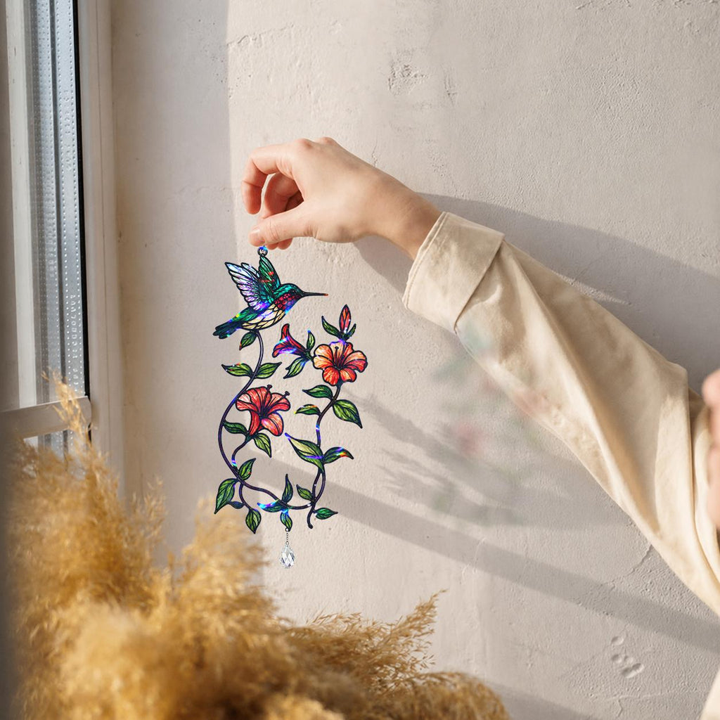 Hand hanging a hummingbird blooming vine holographic acrylic suncatcher near a bright window