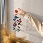 Hand hanging a hummingbird blooming vine holographic acrylic suncatcher near a bright window
