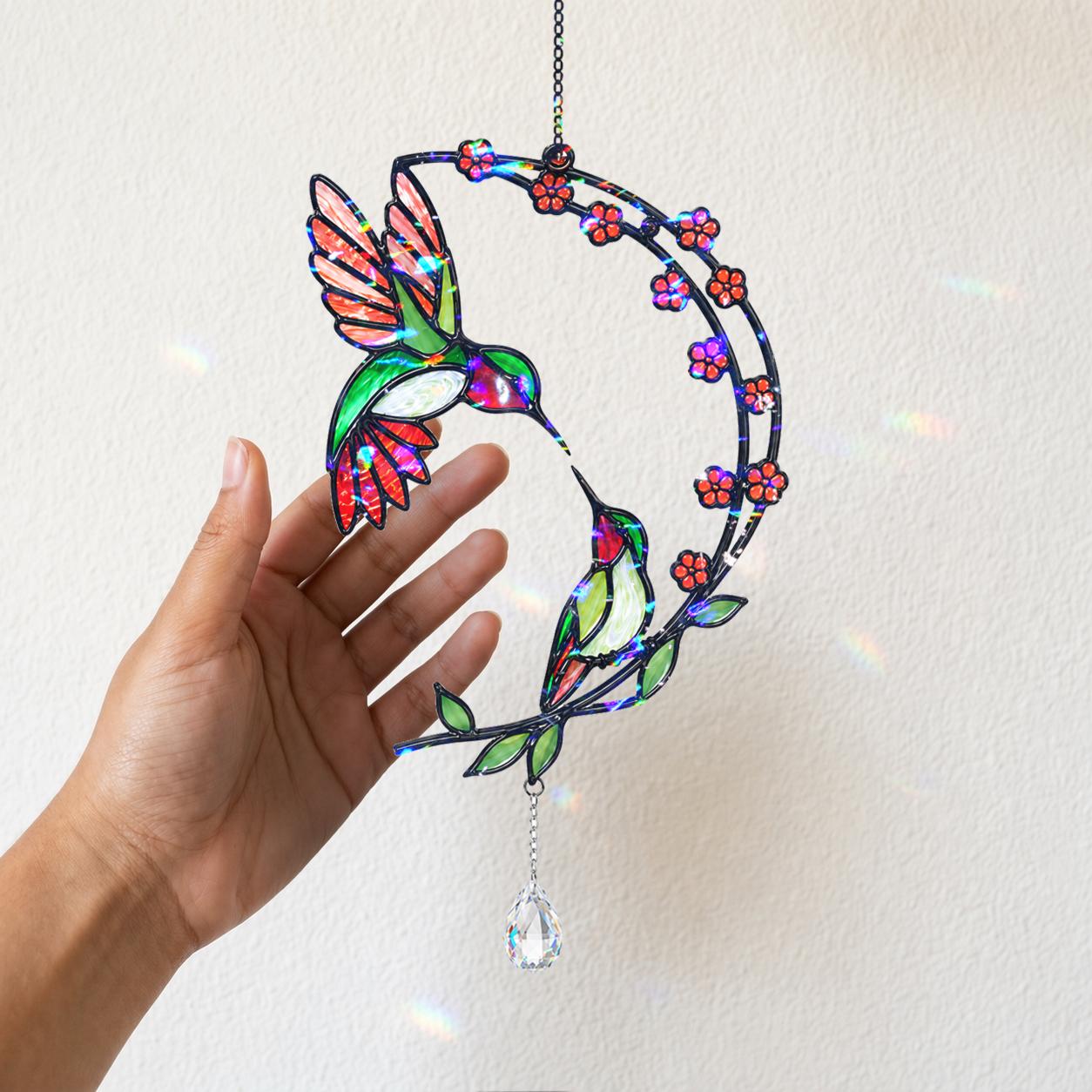 Hand holding a hummingbird cherry blossom moon holographic acrylic suncatcher against a light wall