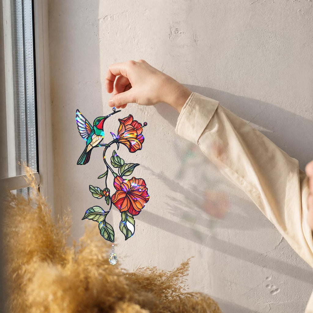 Hand placing a hummingbird hibiscus holographic acrylic suncatcher near a bright window
