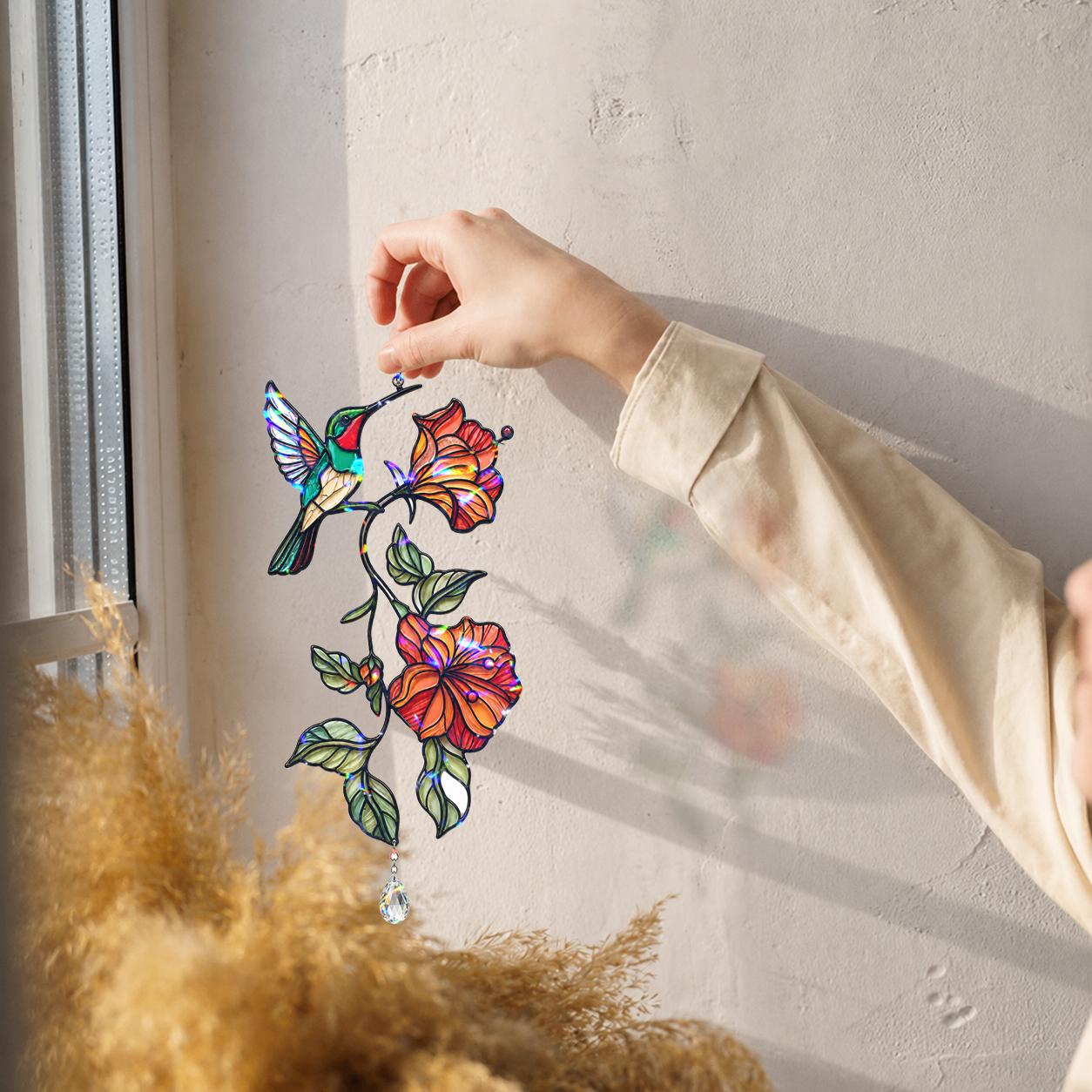 Hand placing a hummingbird hibiscus holographic acrylic suncatcher near a bright window