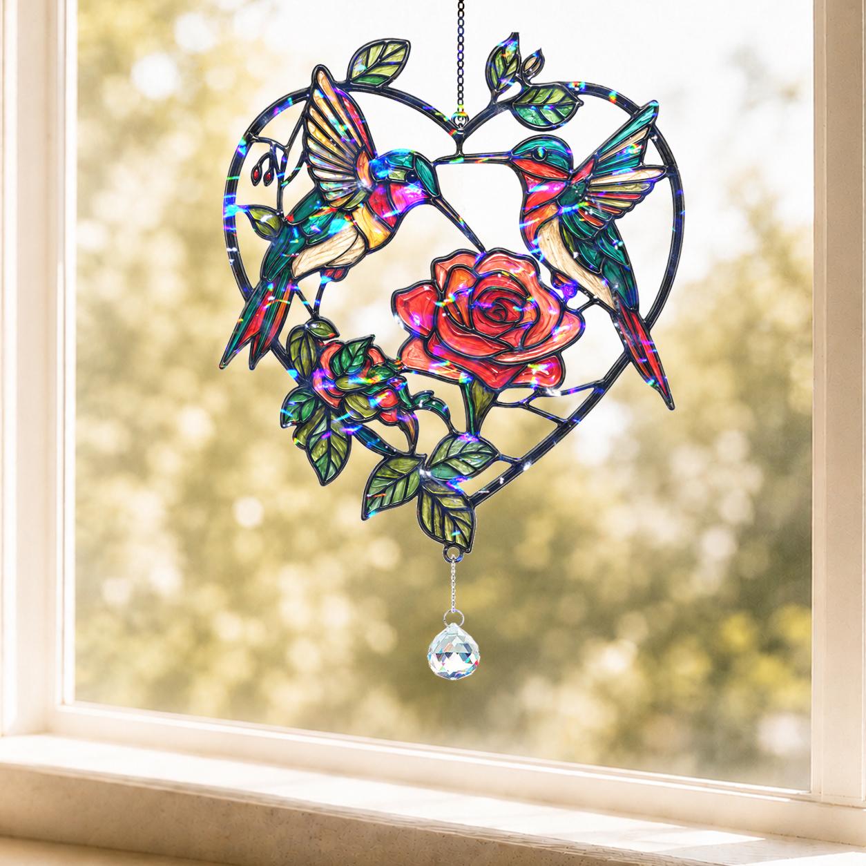 Heart-shaped hummingbird and rose holographic acrylic broken glass suncatcher hanging in a sunlit window.