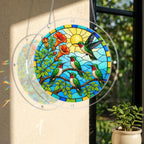 Hummingbird sunrise garden puzzle suncatcher displayed in a bright window beside leafy greenery.