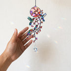 Close-up hand holding hummingbird holographic acrylic suncatcher with floral branch artwork