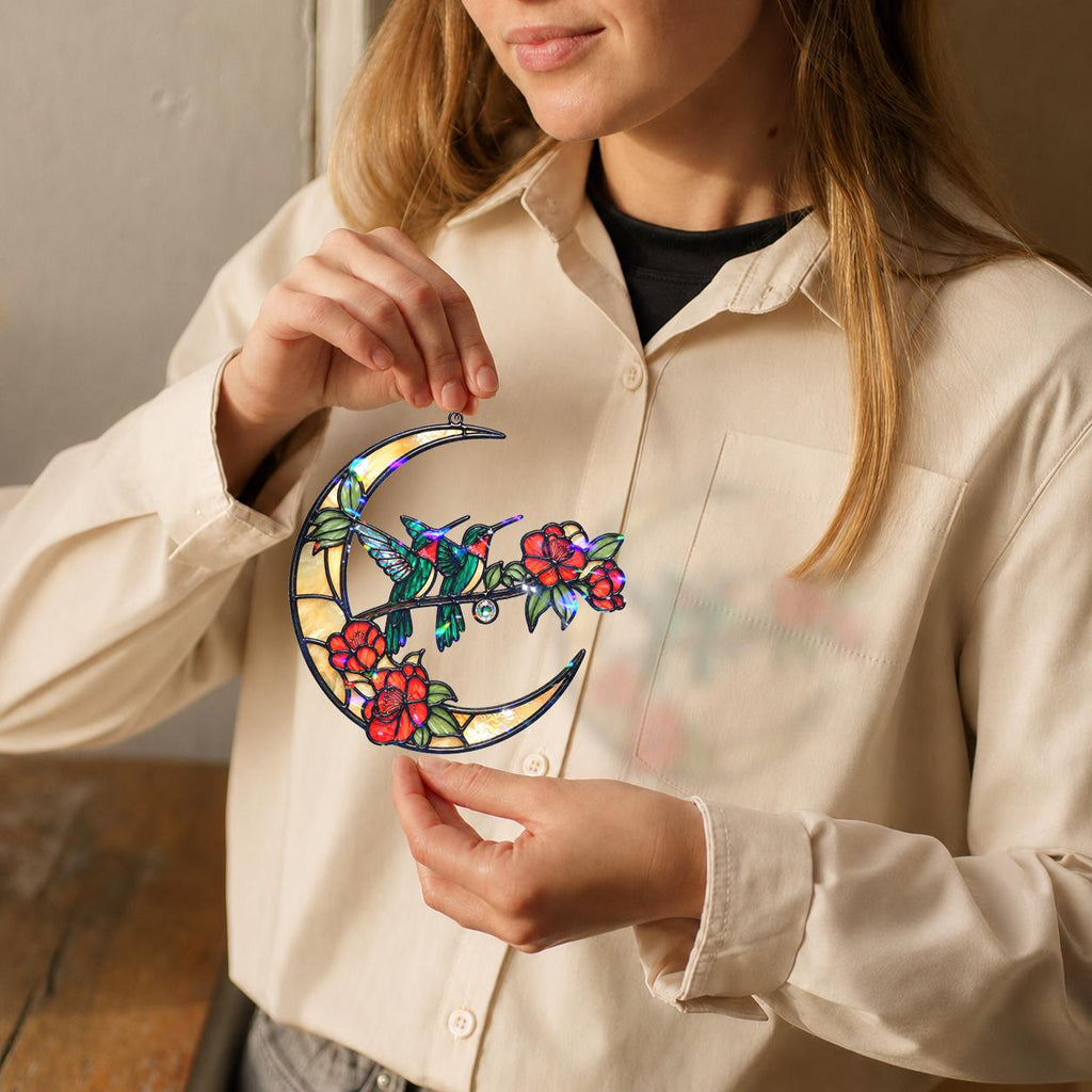 Person holding a colorful stained glass moon with floral design