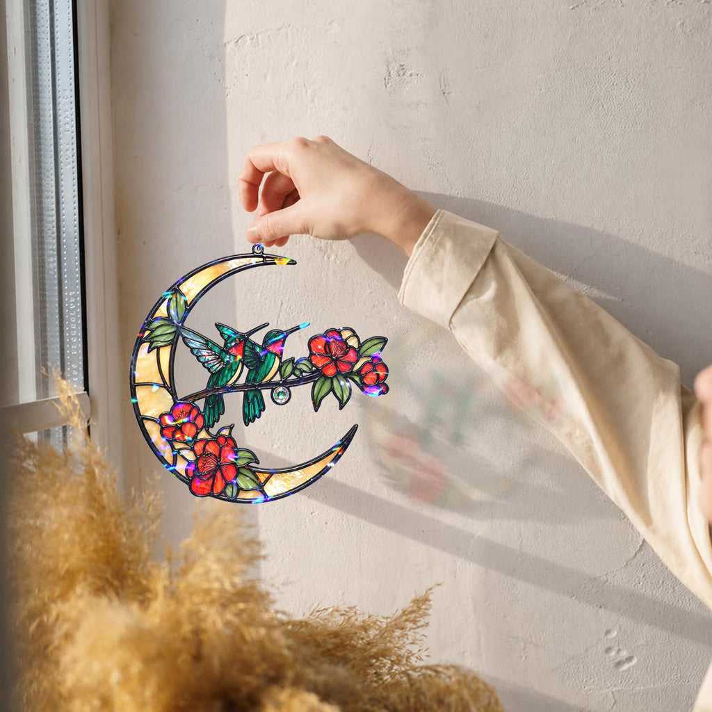 Hummingbird crescent moon holographic acrylic suncatcher hanging by a sunny wall and window