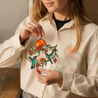 Person holding a hummingbird holographic acrylic suncatcher with fuchsia flowers and sunset design