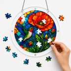 Hands assembling a hummingbird poppy acrylic jigsaw puzzle suncatcher with small colorful puzzle pieces