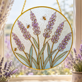 Round stained glass panel with lavender flowers and bees, hanging in front of a window.