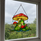 Frog couple reading a book under a mushroom umbrella holographic acrylic suncatcher hanging in a rainy window