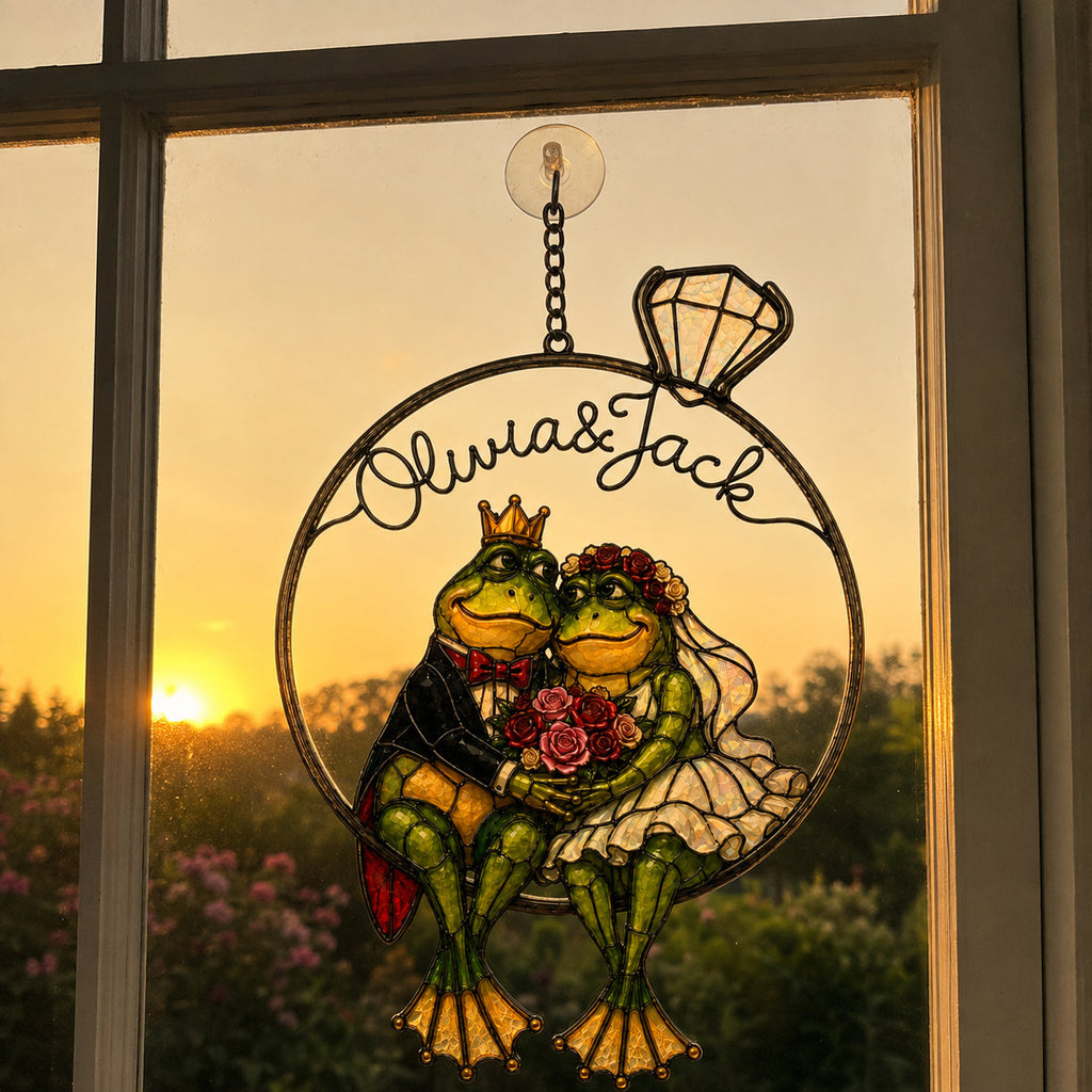 Personalized frog bride and groom ring suncatcher glowing in a window at golden sunset