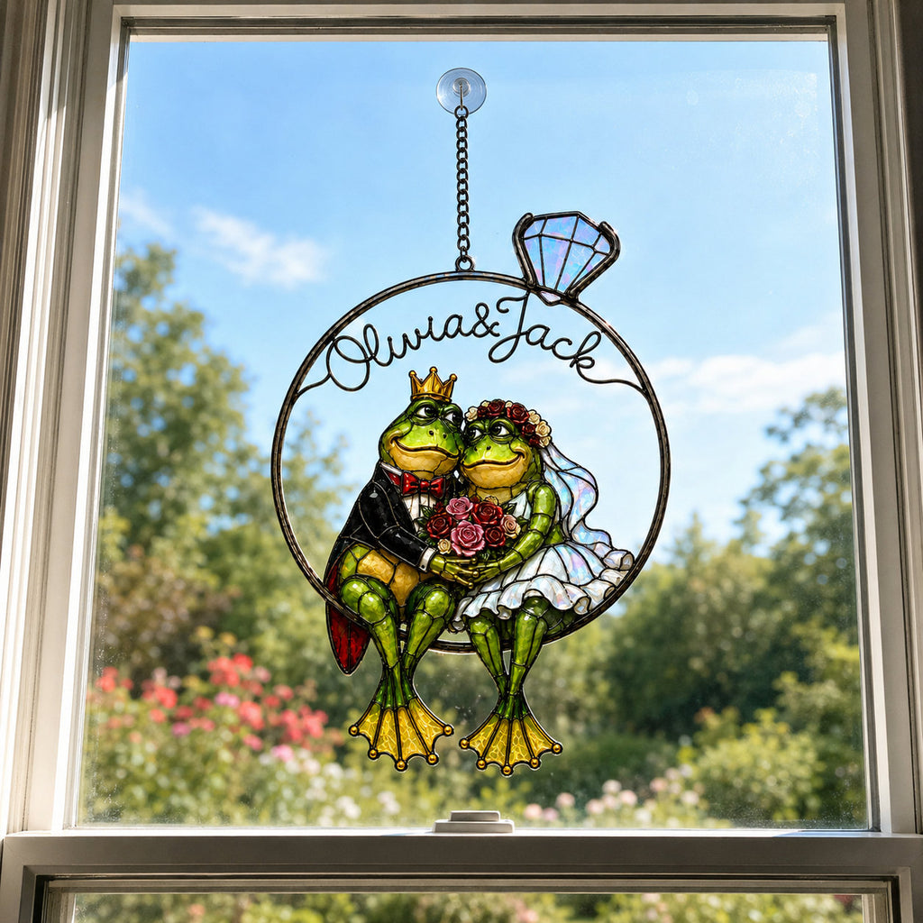 Personalized frog wedding couple suncatcher hanging in a bright window under a blue sky
