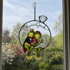 Personalized frog bride and groom suncatcher in a window with white blossoms outside