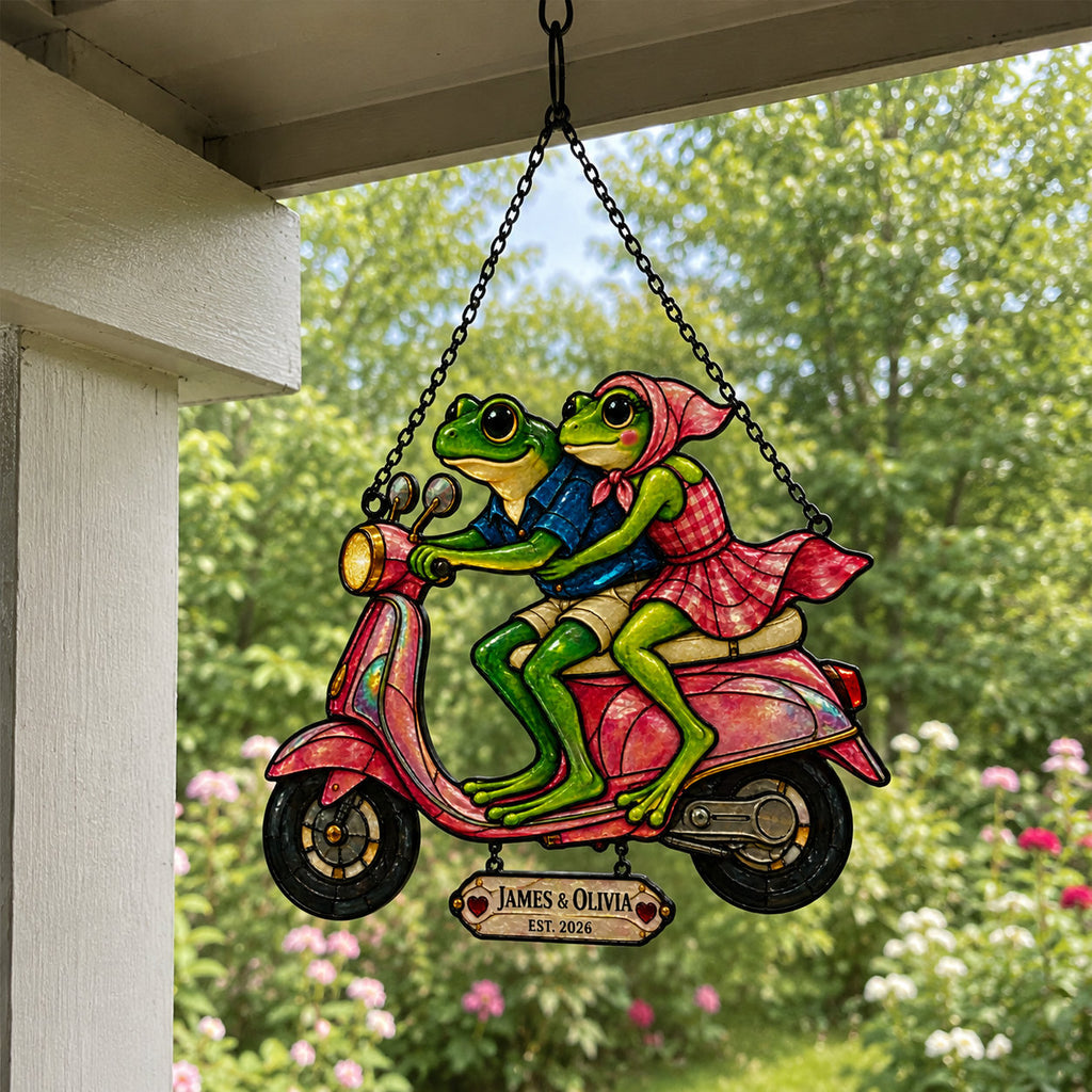 Personalized frog couple scooter suncatcher hanging on a covered porch