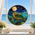 Stained glass panel with sea turtles hanging on a window with a beach view.