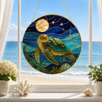 Stained glass panel with sea turtles hanging on a window with a beach view.