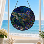Decorative stained glass panel with a turtle design in front of a window with a view of the ocean.