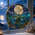 Stained glass panel with a turtle and moon design, set against a window view of water and sky.