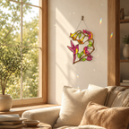 Hummingbirds & Trumpet Vine suncatcher hanging in a sunlit living room nook with cozy seating and plants, rainbow reflections on nearby surfaces.