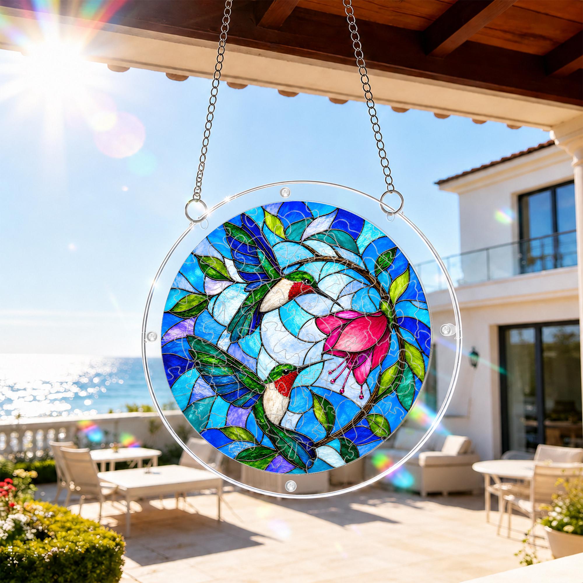 Hummingbird floral acrylic puzzle suncatcher hanging on an outdoor patio window in bright daylight