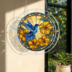 Round acrylic hummingbird puzzle suncatcher hanging in a window with orange hibiscus flowers and golden artwork.