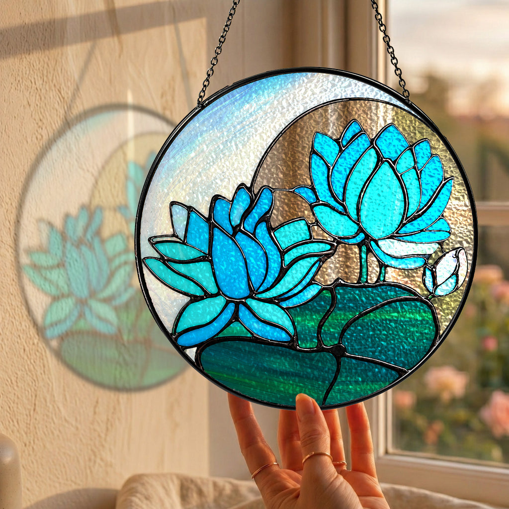 Blue lotus stained glass suncatcher hanging in a sunny window with a garden view