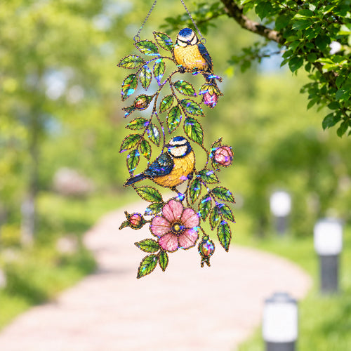 Blue tit and wild rose holographic suncatcher catching sunlight and casting rainbow reflections in a window