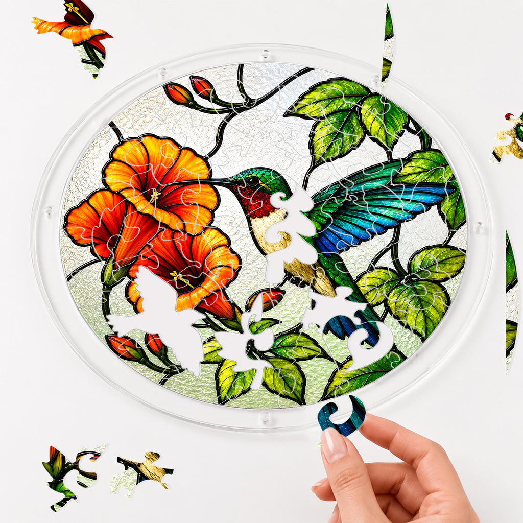 Hand assembling a blue wing hummingbird orange flower acrylic puzzle suncatcher