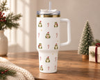 White Christmas frog 40 oz tumbler with handle and straw on a wooden table beside a mini Christmas tree