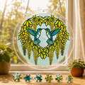Round Citrine Wisteria Duet Hummingbird acrylic puzzle suncatcher hanging in a sunny window with colorful loose puzzle pieces below.