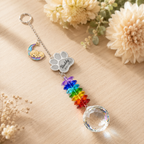 Personalized dog memorial moon crystal suncatcher displayed on a wooden tabletop with crescent moon dog charm, custom paw charm, rainbow crystals, and clear crystal ball