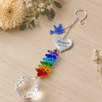 Personalized memorial dove crystal suncatcher displayed on wooden tabletop with custom Margaret heart charm, blue dove charm, rainbow crystal strand, and clear crystal ball