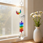Personalized dog memorial Rainbow Bridge crystal suncatcher hanging by a sunny window beside a white vase of daisies