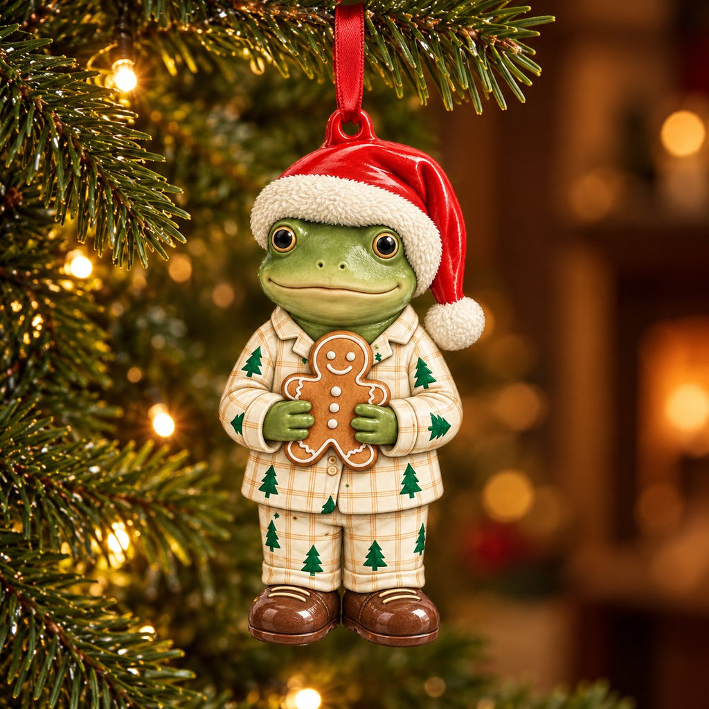 Gingerbread Pajamas frog ceramic ornament: frog in plaid Christmas tree pajamas and a Santa hat hugging a gingerbread man, hanging on a Christmas tree